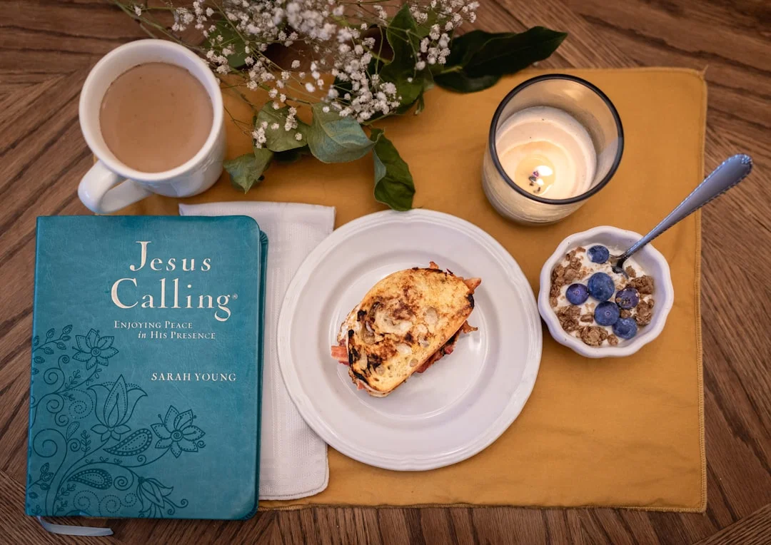 Una pequeña baraja de tarjetas de afirmaciones descansa sobre una mesa de madera, junto a una vela y una taza de café.