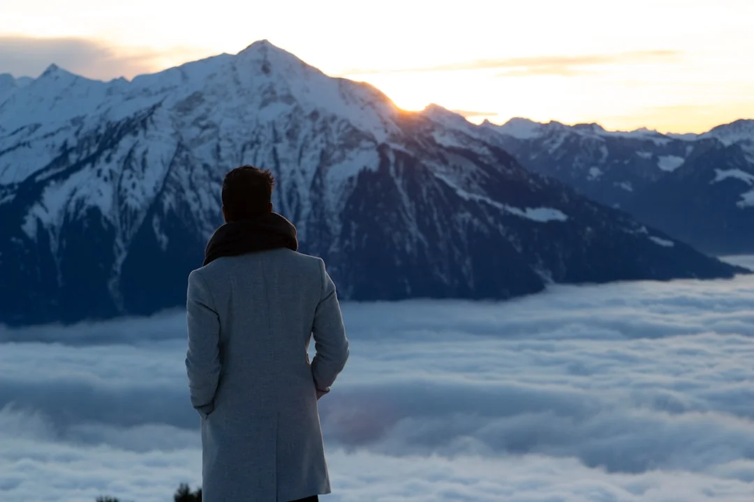 Donna in piedi sulla cima di una montagna al sorgere del sole e sguardo in lontananza