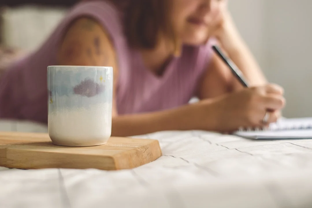 A woman writes thoughtfully in her diary—self-reflection as the first step toward change