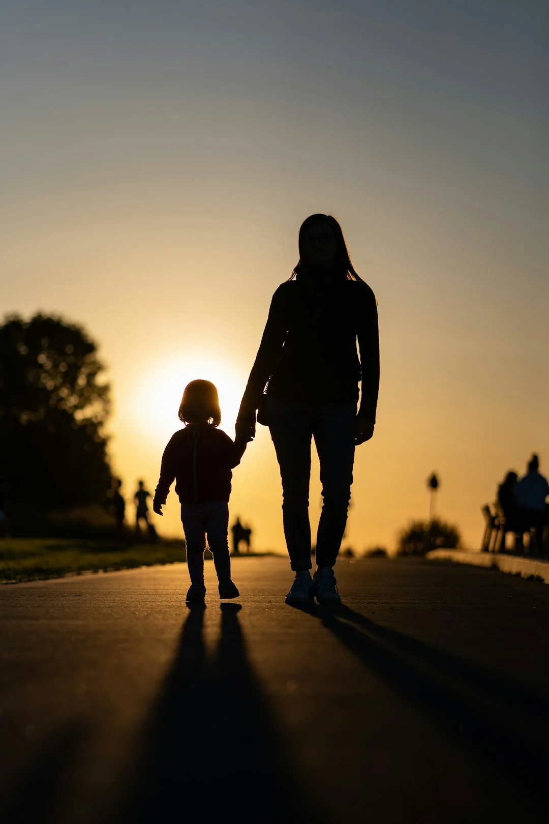 un uomo e un bambino che camminano lungo una strada al tramonto
