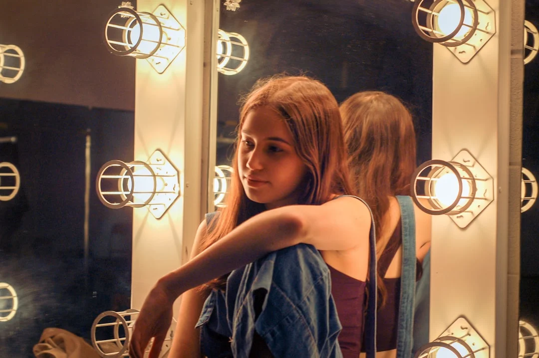 Young girl looks thoughtfully at herself in the mirror