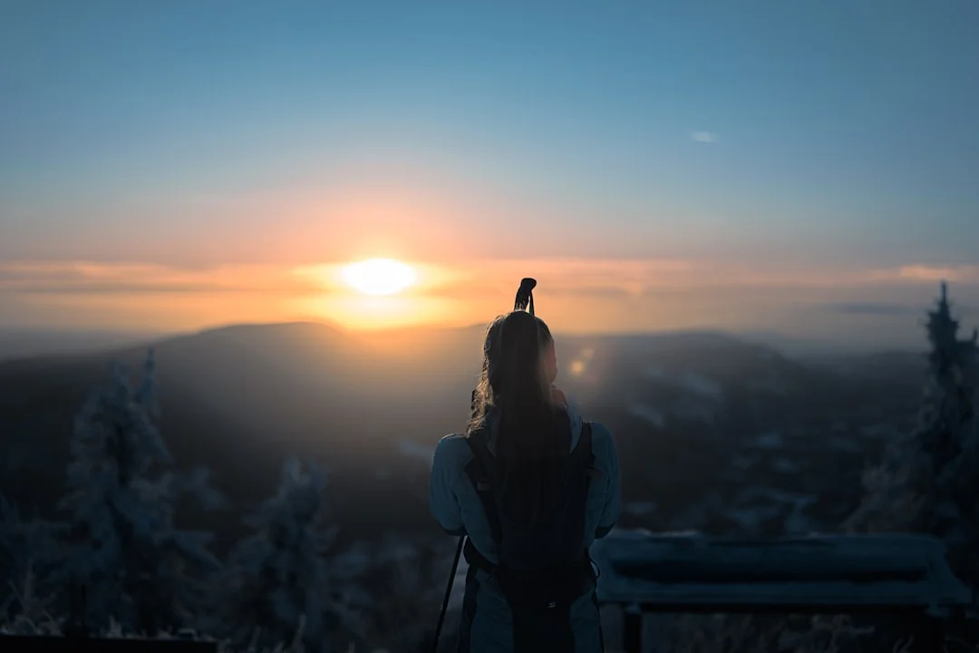 Personne debout au sommet d'une montagne au lever du soleil - symbole de résistance psychique et de force mentale